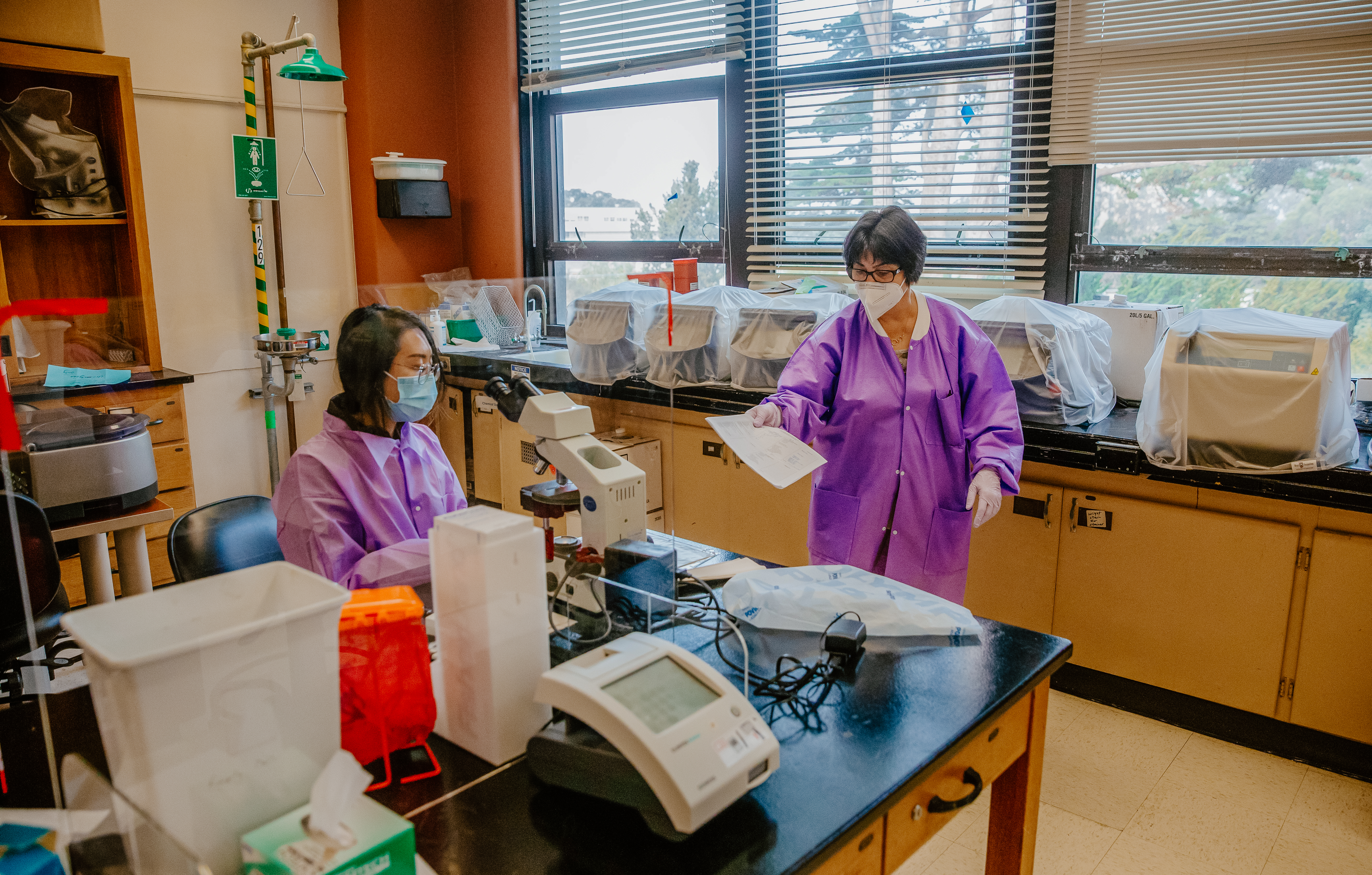 Two people in a lab wearing purple coats.