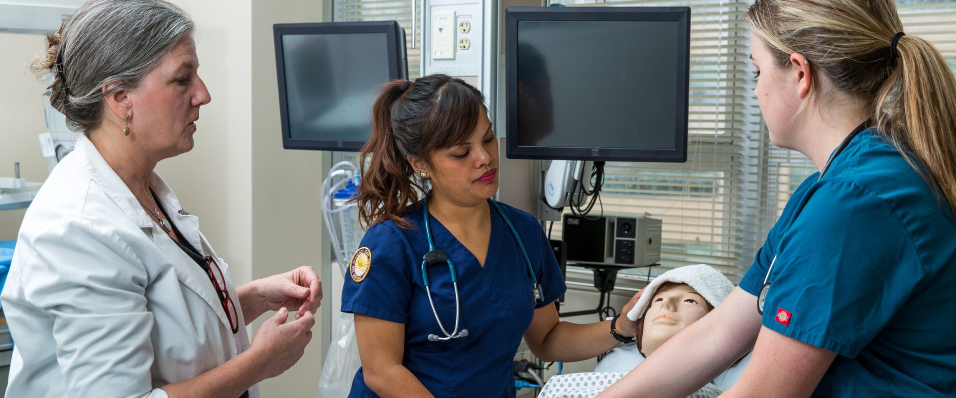 Family Nurse Practitioner students and teacher work on dummy patient