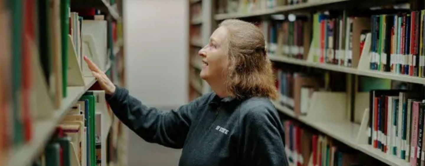 SFSU librarian looking at books in the stacks