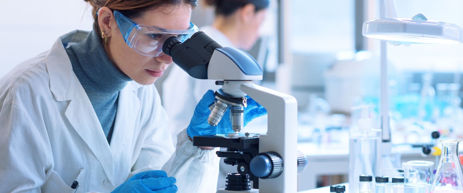 Scientist in a lab looks into a microscope